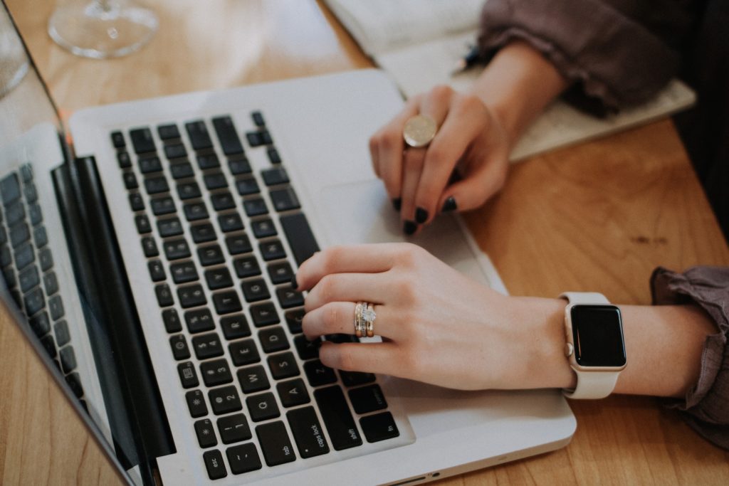 Close up of hands typing on laptop. Person is wearing an Apple Watch.